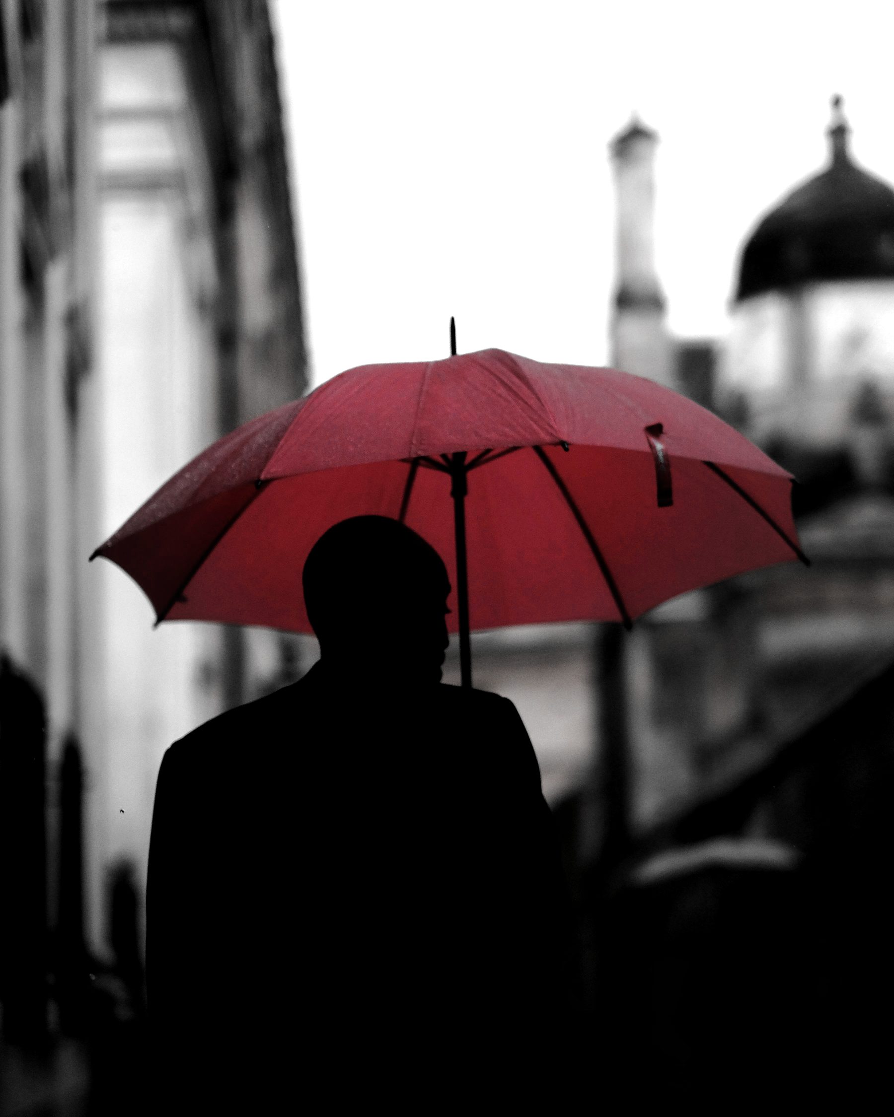Une silhouette sous un parapluie rouge, tout le reste en noir et blanc