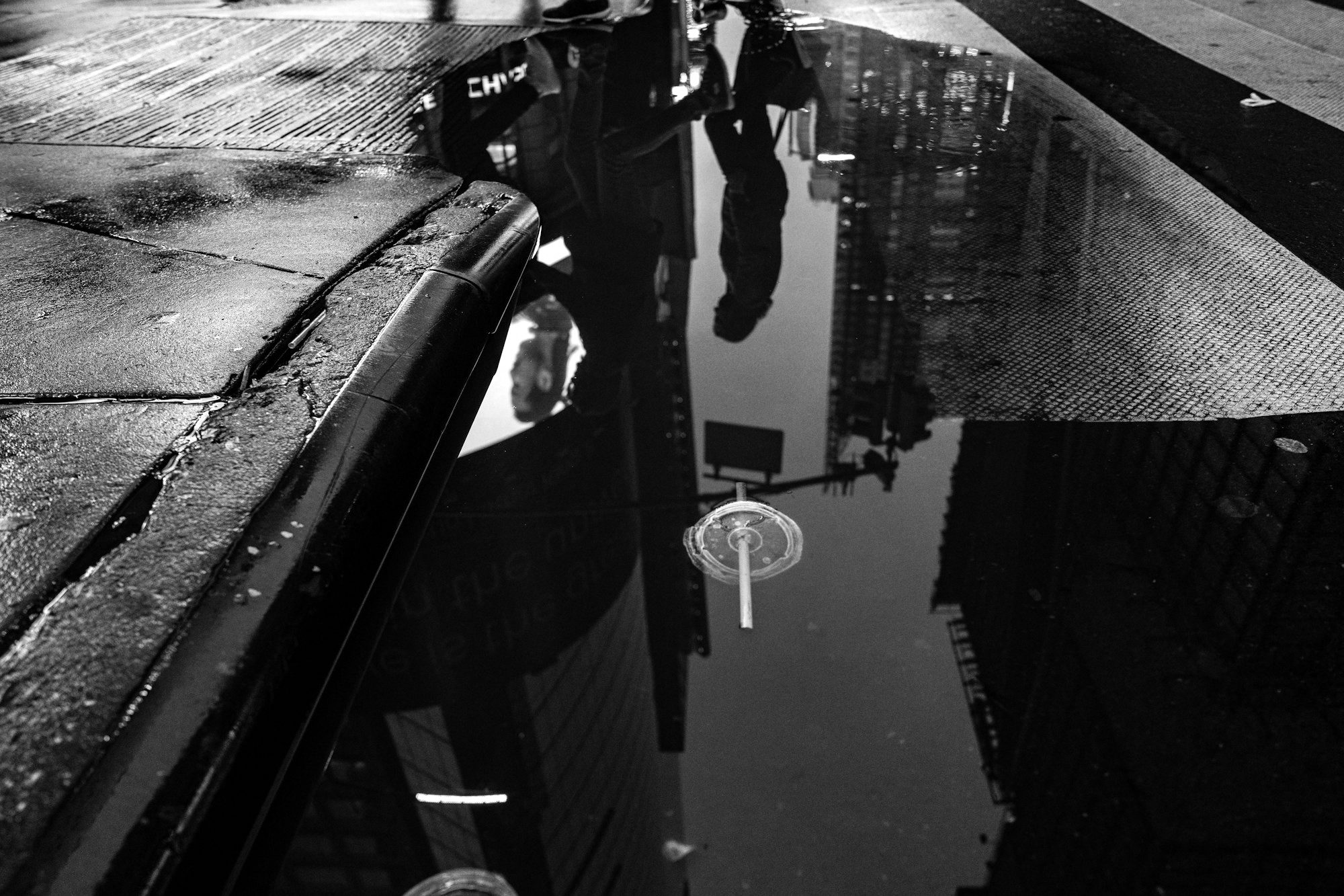 Des pieds et des immeubles reflétés dans l'eau de pluie
